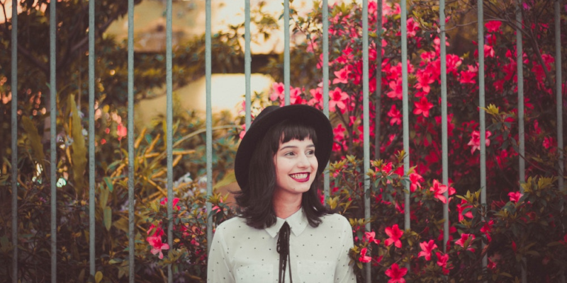 A young woman smiling happily amongst flowers.