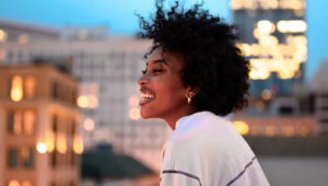 A young woman on a rooftop smiling confidently with healthy teeth.