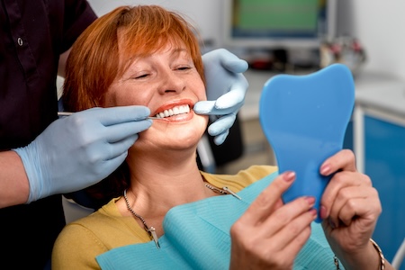 older woman after receiving implant dentures from a dentist in Oceanside